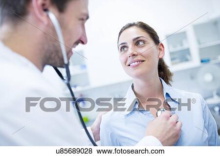 Stock Photo - Male doctor examining female patient.. Fotosearch