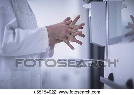 Stock Image - Male doctor using hand sanitiser. Fotosearch