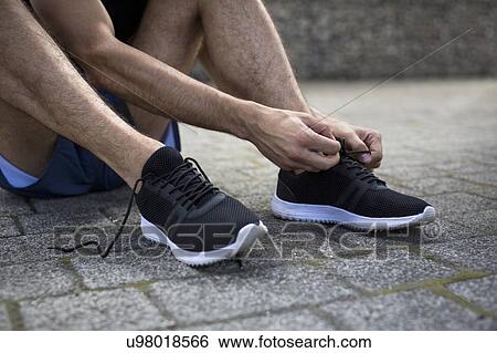 Stock Photograph - Man tying up shoelaces on trainers.. Fotosearch