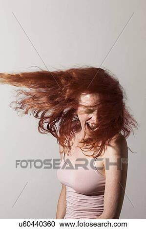 Stock Image - MODEL RELEASED. Angry woman with red hair screaming with rage.. Fotosearch