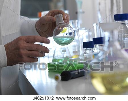 MODEL RELEASED. Chemistry experiment. Scientist preparing a chemical formula in a laboratory flask during a experiment. View Large Photo Image Stock Image - MODEL RELEASED. Chemistry experiment. Scientist preparing a chemical formula in a laboratory flask during a experiment.. Fotosearch