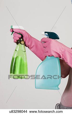 Picture - MODEL RELEASED. Close-up of hands with pink gloves holding cleaning materials.. Fotosearch