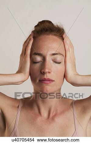 MODEL RELEASED. Close-up of woman covering ears with e1 closed against grey backdrop in studio. View Large Photo Image Picture - MODEL RELEASED. Close-up of woman covering ears with e1 closed against grey backdrop in studio.. Fotosearch