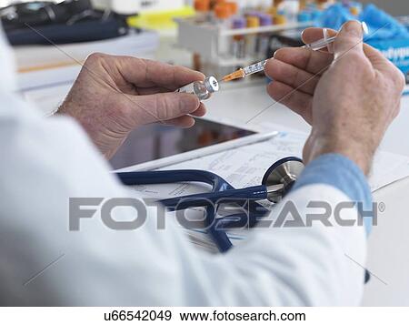Stock Photo - MODEL RELEASED. Doctor preparing a syringe ready for injection.. Fotosearch