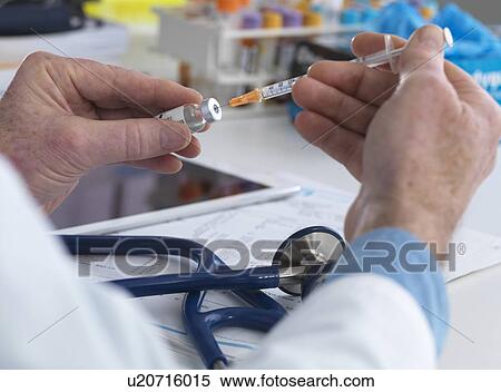MODEL RELEASED. Doctor preparing a syringe ready for injection. View Large Photo Image Stock Photography - MODEL RELEASED. Doctor preparing a syringe ready for injection.. Fotosearch