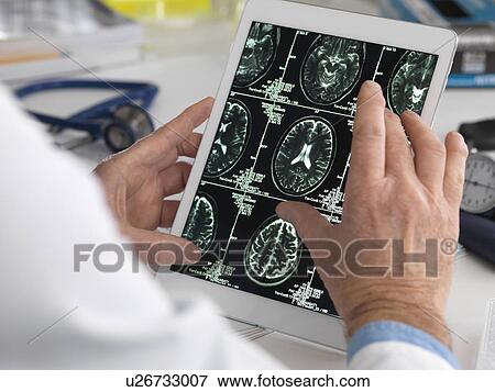MODEL RELEASED. Doctor viewing brain scans on a digital tablet. View Large Photo Image Stock Photo - MODEL RELEASED. Doctor viewing brain scans on a digital tablet.. Fotosearch