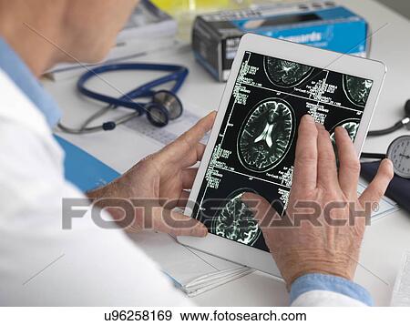 MODEL RELEASED. Doctor viewing brain scans on a digital tablet. View Large Photo Image Stock Photo - MODEL RELEASED. Doctor viewing brain scans on a digital tablet.. Fotosearch