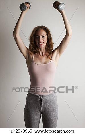 MODEL RELEASED. Happy woman lifting dumb bells over her head during strength exercise. View Large Photo Image Stock Photo - MODEL RELEASED. Happy woman lifting dumb bells over her head during strength exercise.. Fotosearch