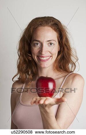 Stock Photo - MODEL RELEASED. Portrait of smiling woman holding red apple.. Fotosearch