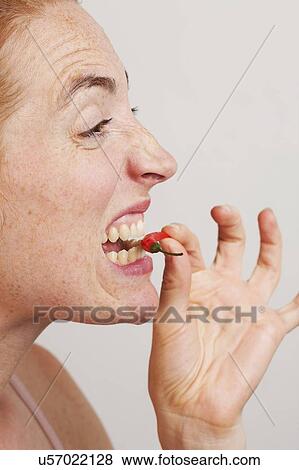 MODEL RELEASED. Profile of woman biting into red chili. View Large Photo Image Stock Photo - MODEL RELEASED. Profile of woman biting into red chili.. Fotosearch