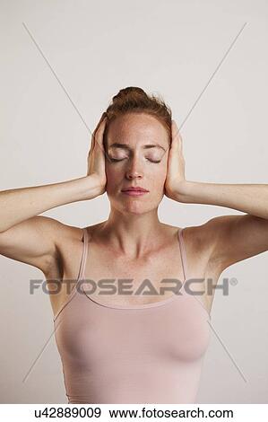 MODEL RELEASED. Woman covering ears with e1 closed against grey backdrop in studio. View Large Photo Image Stock Photo - MODEL RELEASED. Woman covering ears with e1 closed against grey backdrop in studio.. Fotosearch
