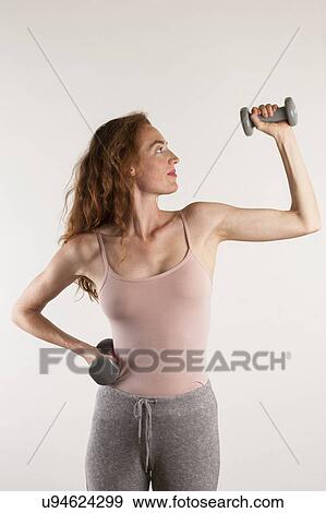 Stock Photo - MODEL RELEASED. Woman exercising with dumb bells.. Fotosearch