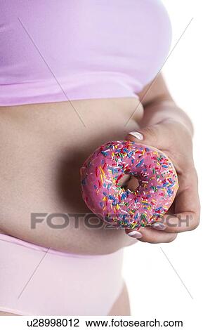 MODEL RELEASED. Woman holding doughnut in front of belly. View Large Photo Image Stock Image - MODEL RELEASED. Woman holding doughnut in front of belly.. Fotosearch