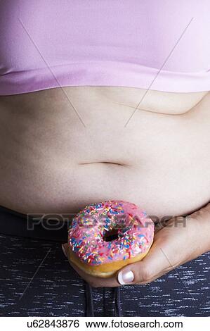 MODEL RELEASED. Woman holding doughnut in front of belly. View Large Photo Image Stock Photograph - MODEL RELEASED. Woman holding doughnut in front of belly.. Fotosearch