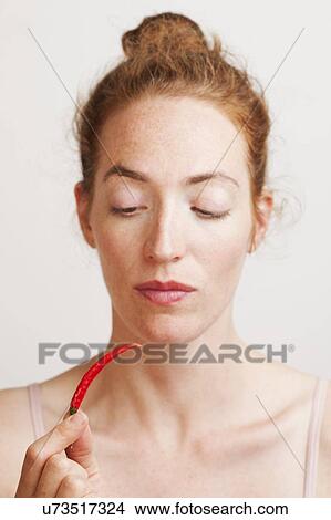 Picture - MODEL RELEASED. Woman holding red chili pepper.. Fotosearch