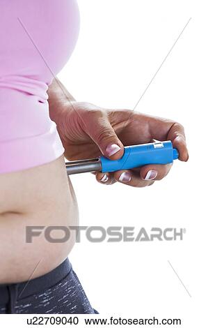 Stock Image - MODEL RELEASED. Woman injecting herself in her side.. Fotosearch