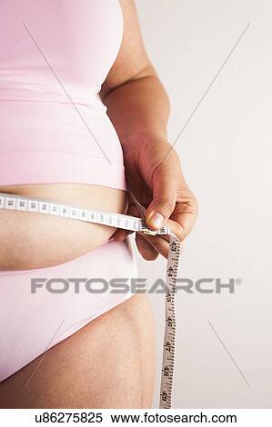Stock Photography - MODEL RELEASED. Woman measuring waist with tape measure.. Fotosearch