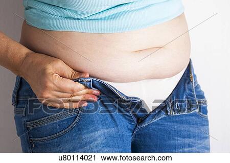 Stock Image - MODEL RELEASED. Woman trying to do up her jeans.. Fotosearch