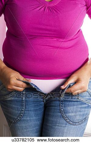 Stock Photography - MODEL RELEASED. Woman trying to do up her jeans.. Fotosearch