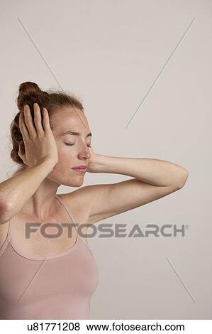 Stock Photo - MODEL RELEASED. Woman turned side-ways with e1 closed covering her ears.. Fotosearch