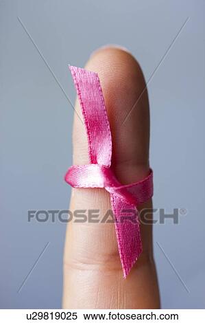 Stock Photography - MODEL RELEASED. Woman with pink ribbon tied to finger.. Fotosearch