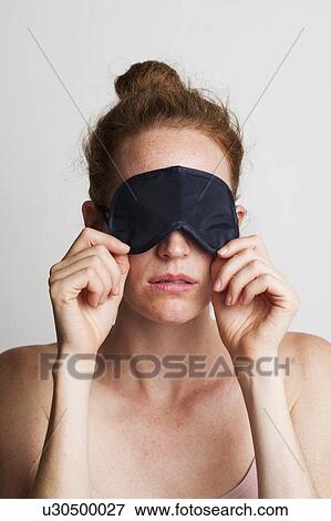 Stock Photo - MODEL RELEASED. Young tired woman wearing a sleeping mask covering her e1.. Fotosearch