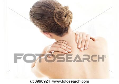 Picture - MODEL RELEASED. Young topless woman in pain touching her back with both hands.. Fotosearch