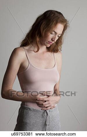 MODEL RELEASED. Young woman holding her stomach with her hands and looking down. View Large Photo Image Stock Image - MODEL RELEASED. Young woman holding her stomach with her hands and looking down.. Fotosearch