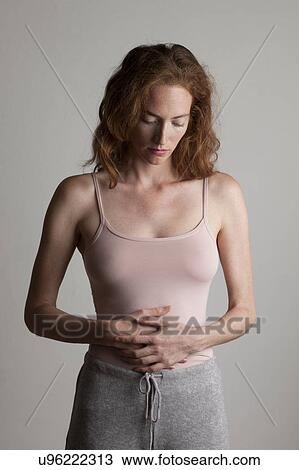 MODEL RELEASED. Young woman holding her stomach with her hands and looking down. View Large Photo Image Stock Image - MODEL RELEASED. Young woman holding her stomach with her hands and looking down.. Fotosearch