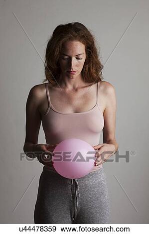 MODEL RELEASED. Young woman holding inflated pink balloon in front of her stomach. View Large Photo Image Stock Photo - MODEL RELEASED. Young woman holding inflated pink balloon in front of her stomach.. Fotosearch