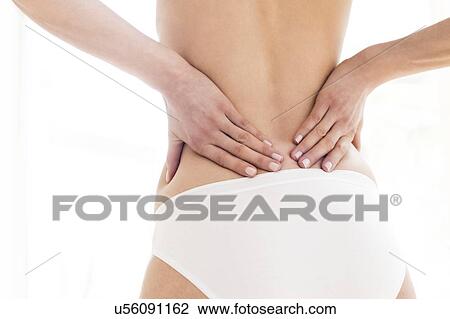 MODEL RELEASED. Young woman in pain rubbing her lower back. View Large Photo Image Stock Image - MODEL RELEASED. Young woman in pain rubbing her lower back.. Fotosearch