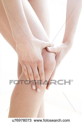 Stock Image - MODEL RELEASED. Young woman in pain rubbing her sore knee.. Fotosearch