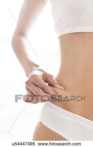 Stock Photography - MODEL RELEASED. Young woman pinching flesh on waist.. Fotosearch