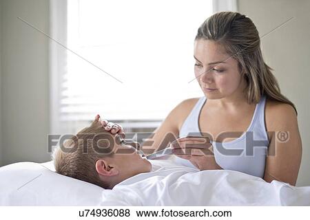 Mother taking son's temperature in bed. View Large Photo Image Stock Photo - Mother taking son's temperature in bed.. Fotosearch