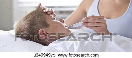 Stock Photography - Mother taking son's temperature in bed.. Fotosearch