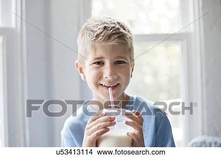 Picture - Portrait of a young boy drinking milk through a straw.. Fotosearch