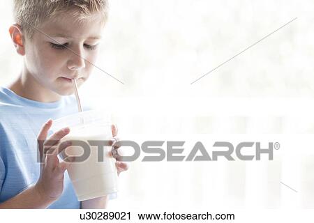 Stock Image - Portrait of a young boy drinking milk through a straw.. Fotosearch