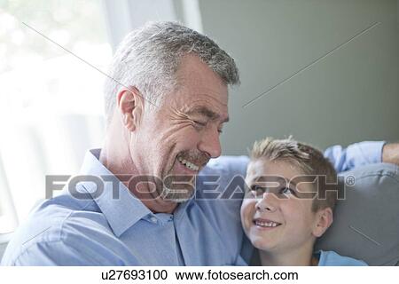 Stock Image - Portrait of grandfather and grandson smiling, face to face.. Fotosearch
