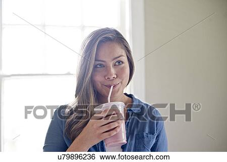 Portrait of young woman drinking through straw. View Large Photo Image Stock Photograph - Portrait of young woman drinking through straw.. Fotosearch