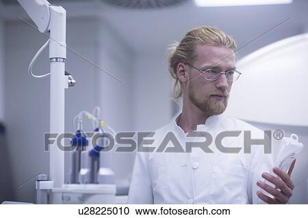 Stock Image - Radiologist holding solution bottle. Fotosearch