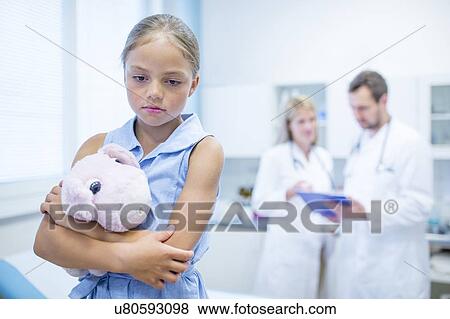 Sad young girl in doctor's room hugging teddy. View Large Photo Image Stock Photo - Sad young girl in doctor's room hugging teddy.. Fotosearch