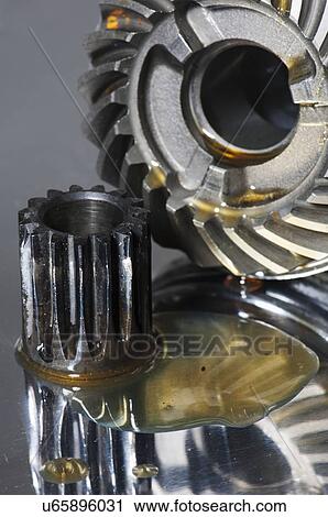 Stock Image - Small and large gears covered in lubricant against a titanium background.. Fotosearch