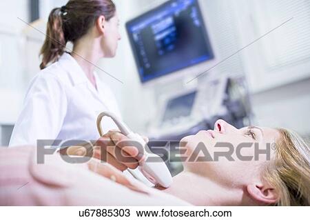 Stock Image - Sonographer performing ultrasound on female patient.. Fotosearch
