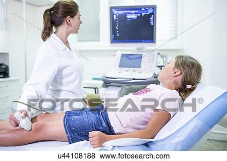 Stock Photo - Sonographer performing ultrasound on girl's leg.. Fotosearch