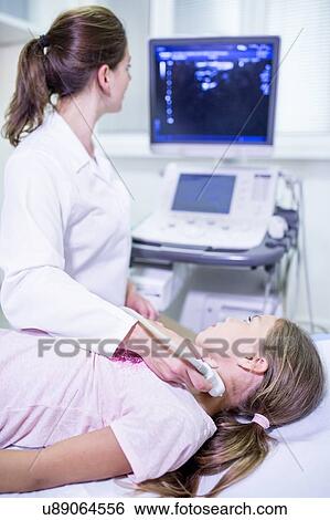 Sonographer performing ultrasound on girl. View Large Photo Image Stock Photograph - Sonographer performing ultrasound on girl.. Fotosearch