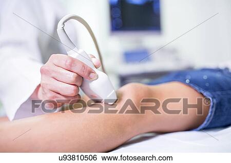 Stock Photograph - Sonographer performing ultrasound on girl's leg.. Fotosearch