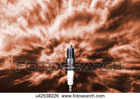 Stock Photograph - Spark plug receiving power and energy in a symbolic dark red sky.. Fotosearch