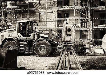 Stock Photo - Surveyor's instrument on construction site with bulldozer and scaffolding.. Fotosearch