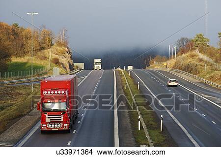 Picture - Trucks on a highway in the early morning with mist in the background.. Fotosearch