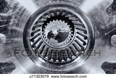 Two steel workers seen through a giant cogwheel axle. View Large Photo Image Stock Photo - Two steel workers seen through a giant cogwheel axle.. Fotosearch